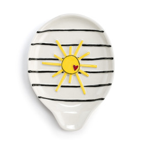 A cream stoneware spoon rest with black stripes and a raised yellow sun.