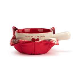 A cream handled soup bowl with a red interior inside a red fabric cozy. The bowl says "bowl full of jolly" with a red heart.