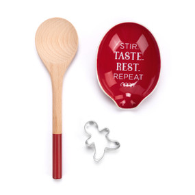 A holiday kitchen accessory set including a wood spoon, a gingerbread cookie cutter and a red ceramic spoon rest that says "Stir. Taste. Rest. Repeat."
