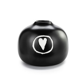 A black ceramic round squat bud vase with a white heart in a circle on the front.