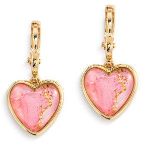 A pair of gold dangling earrings with a heart shaped charm and pink and gold artwork inside.