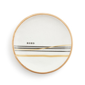 A small round white ceramic trinket dish with black and gold horizontal lines and "xoxo" in the middle.