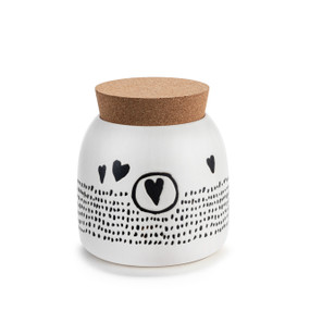 A small round white ceramic canister with black dots and hearts. The canister has a cork lid.