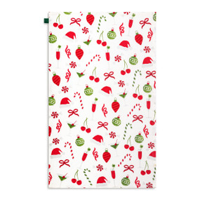 A white kitchen towel with illustrations of martinis, peppermint candies and Christmas ornaments, displayed laid out flat.