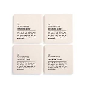 A set of four white ceramic coasters with the saying "RE: Out of Office Chasing the Sunset" with a short write up about someone watching the sunset in the mountains.