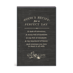 A black wall art with an illustration of Pooh and Piglet with a message about Pooh's recipe for a perfect day.