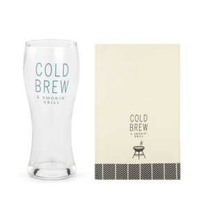 A clear pilsner glass that says "Cold Brew & Smokin' Grill" next to a cream towel with the same saying and a chevron pattern at the bottom.