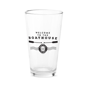 A clear pint glass with the saying "Welcome to the boat house. Dogs float for free".
