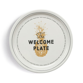 A round cream stoneware plate with a rim accent and pineapple in the center. The plate says "The Welcome Plate" and has a special message about moving to a new home.