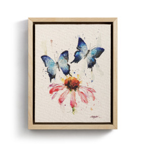 A watercolor wall art of blue butterflies and a pink coneflower in a light wood frame.