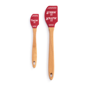 A set of two red spatulas. The larger says "Stirrin' It Scrapin' It" and the smaller says "Tastin' It".