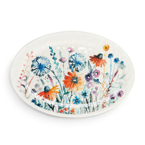 Top down view of a large white oval melamine platter with a meadow floral pattern on top.