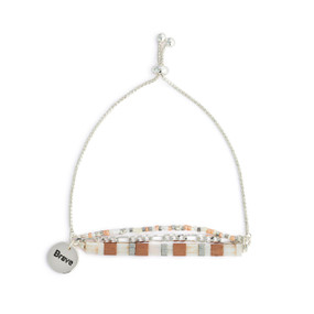 A silver chain adjustable bracelet with beads and tiles in brown, cream and gray. The bracelet also has a silver round charm that says Brave.