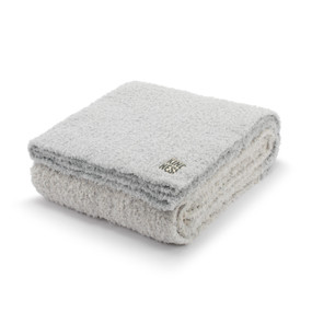 A gray and blue blanket with a tag that says "Kindness" displayed folded.