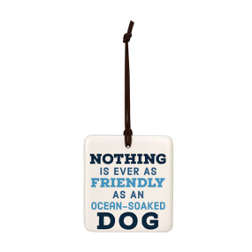 A square white hanging tile magnet ornament with the saying "Nothing is ever as friendly as an ocean-soaked dog".
