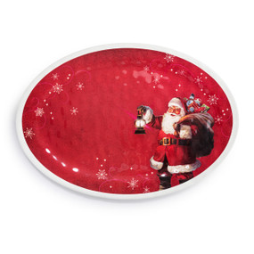An oval red and white melamine platter with an old fashioned Santa carrying a bag of toys and a lantern.