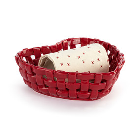 A heart shaped red woven ceramic basket with a cream towel rolled and displayed inside.