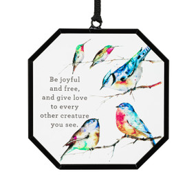 A hexagon shaped suncatcher with watercolor songbirds and the saying "Be joyful and free, and give love to every other creature you see".