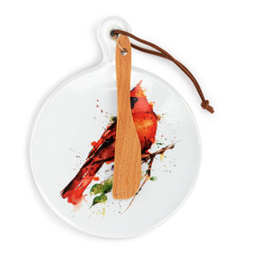 A round ceramic white mini serving board with a watercolor image of a cardinal. The board has a small wood knife attached.