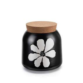 A small round black ceramic canister with a bold white flower. The canister has a cork lid.