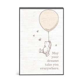 A wall art of Winnie-the-Pooh hanging from a balloon with the saying "May your dreams take you everywhere".