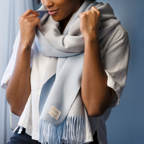 A woman wearing a light blue fringed giving wrap.