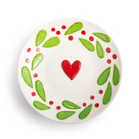 A white ceramic bowl, with holly leaves and berries and a red raised heart in the middle.