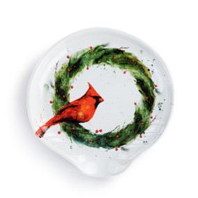 A white ceramic spoon rest with a watercolor image of a red cardinal in a green wreath.