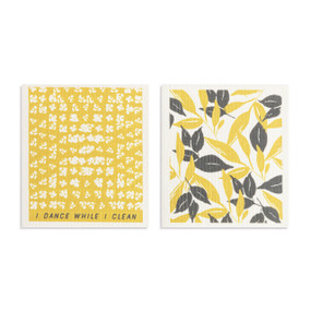 Two yellow and gray biodegradable dish cloths. One is a yellow and gray leaf pattern, and the other is yellow with white flower illustrations and the saying "I dance while I clean".