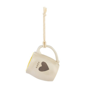 A cream ceramic mini mug that says "XOXO" with the image of a heart on the front, shown hanging with a coffee pod inside.