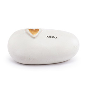 A white stoneware rock with a raised gold heart and xoxo on the top.