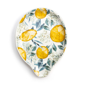 Top down view of a cream ceramic spoon rest with a drawing of lemons and leaves in green and yellow.