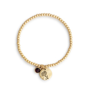 A gold beaded bracelet with a white carnation flower round charm and garnet colored stone.