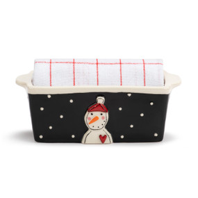 A mini ceramic loaf pan with a black exterior that has a raised snowman on the front and a red and white striped towel rolled inside.