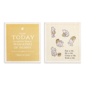 Two biodegradable dish cloths in light and dark yellow. One says "May Today be sweeter than a Smackerel of Hunny" and the other has illustrations of Pooh and the saying "Eat a bit. Sit a bit. Clean a bit. Rest a bit.".