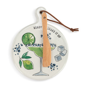 A round ceramic white mini serving board with an illustration of a margarita and the saying "Ready to Shake It Up". The board has a small wood knife attached.