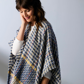 A woman wearing a woven textured wrap in shades of blue and yellow.