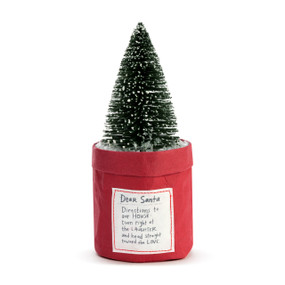 A fake green tree inside a red paper planter that has a tag attached with a note to "Dear Santa".