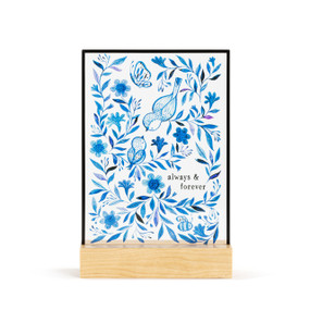 A large rectangular suncatcher in a light wood base. The image is various flowers and birds in blue and the saying "always & forever".