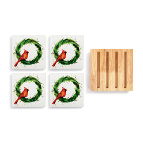 A set of 4 ceramic coasters with a watercolor image of a red bird in a green wreath next to a square wood board with 4 slots for holding the coasters.