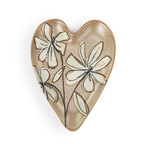 A dull gold heart shaped ceramic spoon rest with a cream magnolia illustration on it.