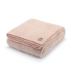 A rose pink blanket with a tag that says "Kindness" displayed folded.