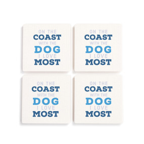 A set of four white ceramic coasters with the saying "On the coast with the dog I love the most".