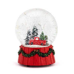 A musical snow globe with a red wood base and a red truck among the trees inside.