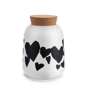 A round white ceramic canister with black hearts. The canister has a cork lid.