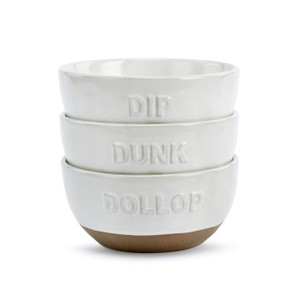 Three white ceramic bowls with tan textured bases each with a different raised word on the front. Words include Dip, Dunk and Dollop. The bowls are displayed stacked together.