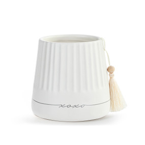 A small round white ceramic cachepot with XOXO on the front with a cream tassel.