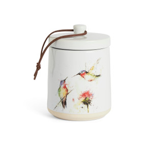 A white ceramic candle with watercolor hummingbirds and a flower on the outside with a removable lid.