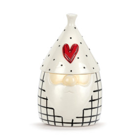 A white ceramic planter in the shape of a gnome. The main planter is black and white check with the nose and beard of the gnome. The hat is a lid with black dots and a raised red heart.
