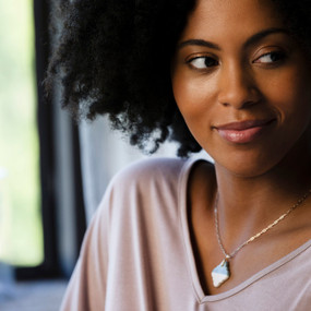 Close up of a woman wearing a diamond shaped diffuser necklace in blue and white.